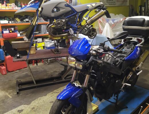 Motoratelier Di Giulini Fabrizio: due moto in riparazione su piattaforme elevatrici, officina specializzata in servizi per motociclisti e viaggi.