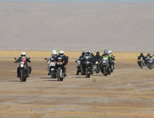 Gruppo di motociclisti in tour organizzato con Motorizzonti su moto da viaggio in un paesaggio desertico.