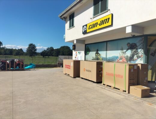 Concessionaria Motorpama: vista esterna con quad in cassa, scatole di accessori moto Yadea e Lambretta e vetrina con immagini di motociclisti.