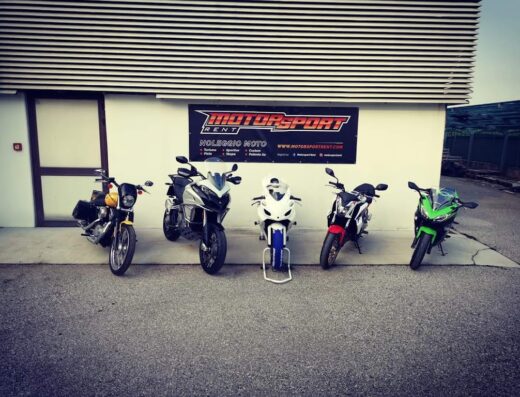 Noleggio moto: fila di motociclette di diversi modelli e colori presso Motorsport Rent, con opzioni custom, sportive, scooter e Vespa. Servizi di affitto moto.