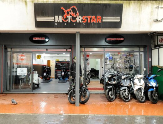 Showroom e officina Motorstar Napoli con scooter e moto esposte, officina visibile con moto in riparazione, vendita scooter Piaggio, SYM, Peugeot