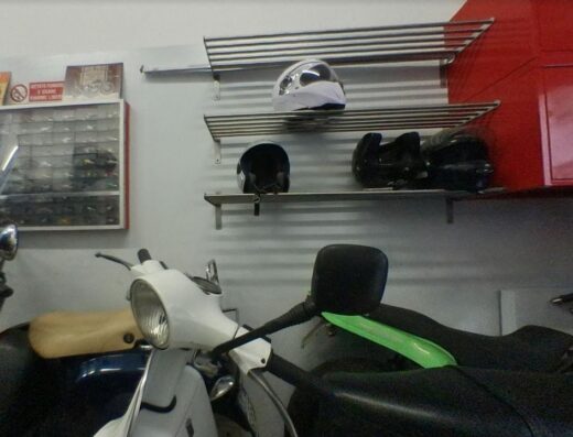 Interno di Motosolution con scooter classici, caschi da moto su scaffali. Accessori e ricambi per la personalizzazione e manutenzione della tua moto.