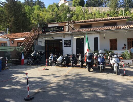 MotoSprint Next dealership with a row of motorcycles and scooters parked outside, showcasing Italian design and motorcycle culture.