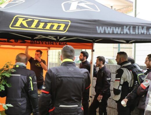 Motoviaggio Store di Gionata Nencini: Gruppo di motociclisti sotto un gazebo Klim, durante un evento o raduno motociclistico. Abbigliamento tecnico da moto in evidenza.