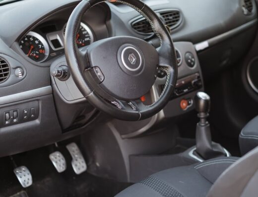 Interni auto: cruscotto, volante Renault con cuciture, sedili sportivi, pedaliera in metallo. Dettagli rifiniti per auto curata.