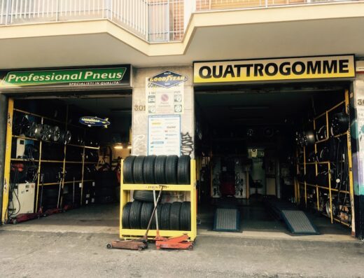 myGOM - QUATTROGOMME di QUATTROMANI CARMINE: Facciata di un negozio di pneumatici "Professional Pneus" e "QUATTROGOMME", con scaffali di pneumatici e cerchioni in esposizione. Servizi di vendita e riparazione di pneumatici per auto e moto.