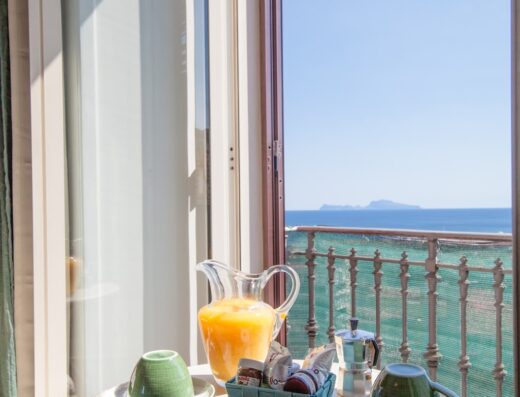 Colazione con vista mare a NapoliCentro Mare Sea View Rooms & Suites. Brioche fresche, succo d'arancia e caffè per un risveglio perfetto.