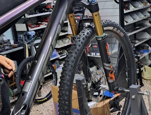 Primo piano di una mountain bike in riparazione presso Noe' Moto & Bike S.R.L., con attrezzi e accessori visibili. Servizio di assistenza e vendita di biciclette.