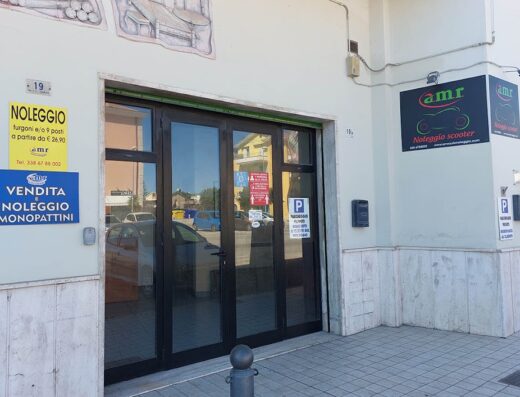 Ingresso negozio AMR con cartelli "Noleggio e Vendita Monopattini" e "Noleggio Scooter", servizio di noleggio furgoni, scooter e monopattini