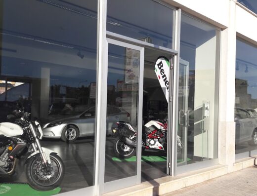 Showroom Novar Trade con vetrine che espongono moto Benelli, cartelli prezzi e auto parcheggiate. Servizi di vendita moto e accessori.