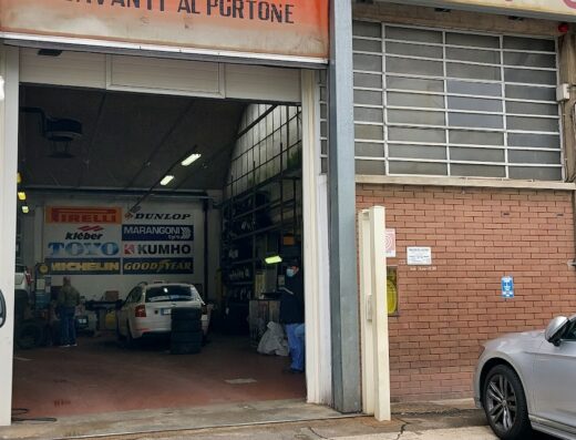Nuova Casa Del Pneumatico Mastro Michelin: officina di riparazione e vendita pneumatici con cartello "Non sostare davanti al portone", marchi Pirelli, Dunlop, Kleber, Kumho, Michelin e Goodyear.