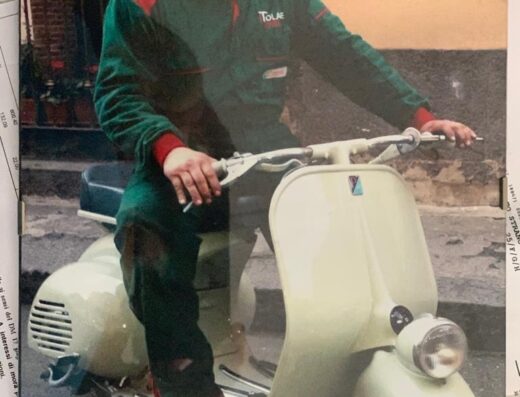 Maurizio Strano in tuta da meccanico su una Vespa d'epoca, specialista in moto e scooter, officina specializzata