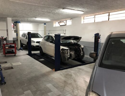 Interno dell'officina auto moto di Passantino Pietro con auto su ponte sollevatore e veicoli in riparazione.