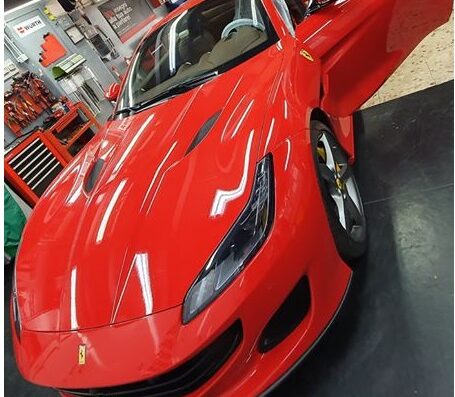 Officina Costanzo Snc: Ferrari rossa in officina con sportello aperto per riparazione o manutenzione. Servizi auto di lusso.