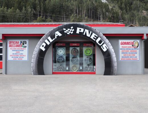 Officina Meccanica PILA PNEUS, gommista e meccanico a Pila, Aosta. Entrata a forma di pneumatico con esposizione di cerchi in lega. Servizi di riparazione, sostituzione pneumatici e assetto ruote.