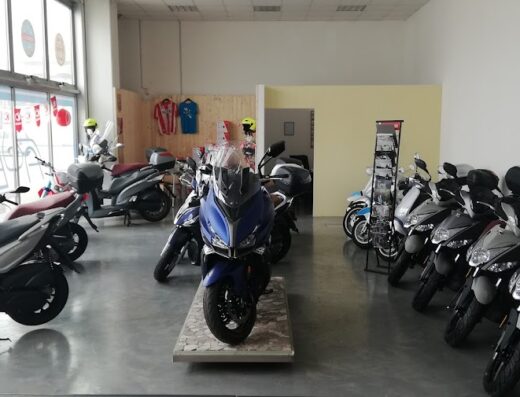 Interno dell'officina moto ABI Service con esposizione di scooter Kymco di vari modelli e colori, pronti per la vendita e l'assistenza.