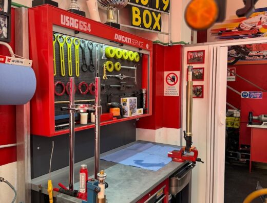 Interno dell'Officina Moto71 di Nico Logiudice con banco da lavoro attrezzato per la manutenzione di moto Ducati, utensili USAG, trofei, e cartelli decorativi di Valentino Rossi.