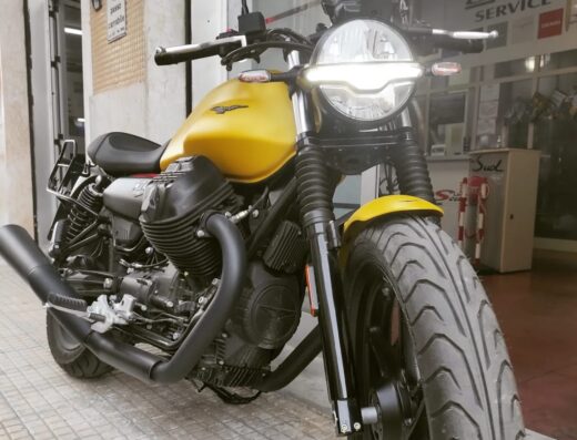 Moto Guzzi gialla esposta davanti all'Officina Piaggio Scuderi, specializzata in servizi per moto Guzzi, Aprilia e Ligier.