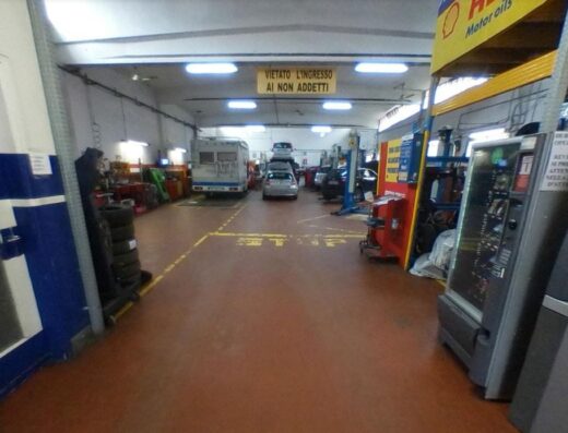 Interno dell'Officina Poiana Raffaele, con auto in riparazione, camper e cartello "Vietato l'ingresso ai non addetti".