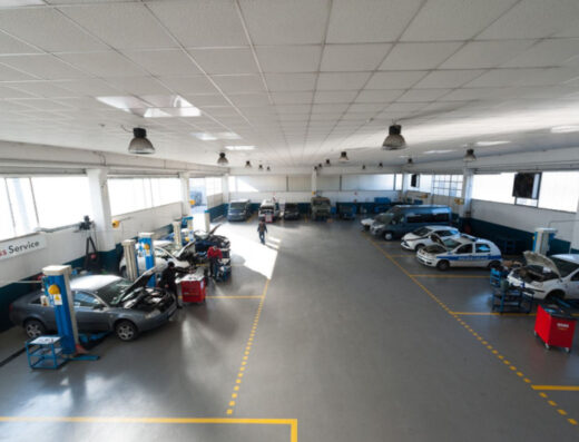 Interno di Officine Meccaniche Cimep con auto in riparazione, furgoni e auto della polizia locale. Servizio di assistenza e manutenzione veicoli.