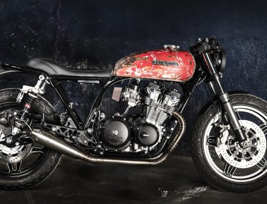 Honda cafe racer vintage con serbatoio rosso sbiadito, ideale per appassionati di moto custom e officine specializzate.