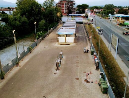 Autolavaggio Opplà 24H con moto parcheggiata, box lavaggio, aspirapolvere moto e vista panoramica sulla città.