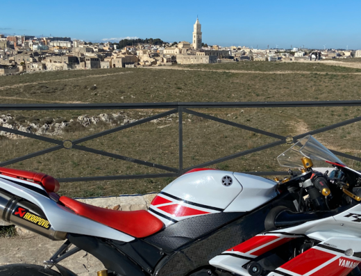 Otello Moto: Yamaha R1 sport motorcycle with Akrapovic exhaust system parked overlooking the city of Matera, Italy. Motorcycle travel.