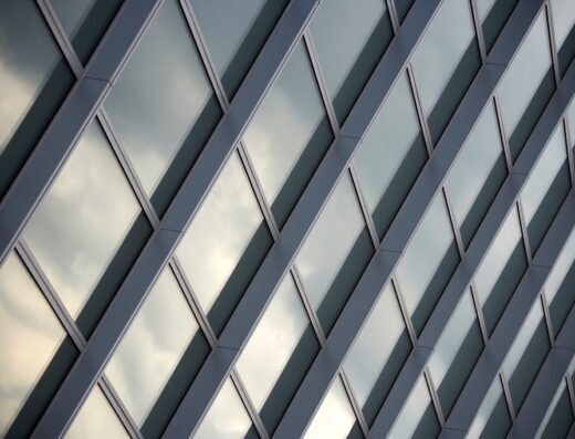 Dettaglio architettonico dell'Oval Lingotto Fiere a Torino, con vetrate a losanga che riflettono il cielo.