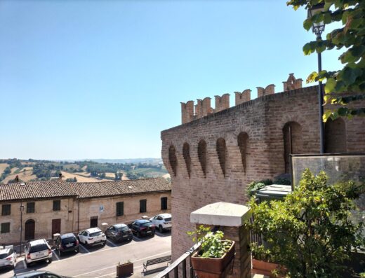 Vista panoramica su Palazzo Boscareto, con parcheggio auto, architettura storica e paesaggio collinare, ideale per motociclisti e ciclisti in cerca di garage moto e box bici.