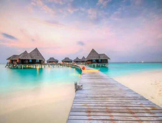 Palafitte sull'acqua turchese alle Maldive, collegate da un pontile in legno, per un viaggio esotico e rilassante offerto da Viaggi Di D'Ascari Davide