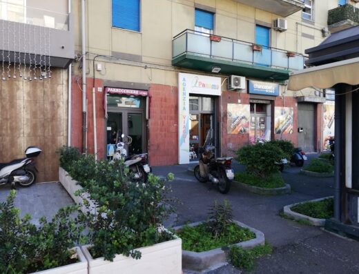 Several scooters are parked outside a Panama travel agency and other shops on a city street. The scooters are different colors and styles.