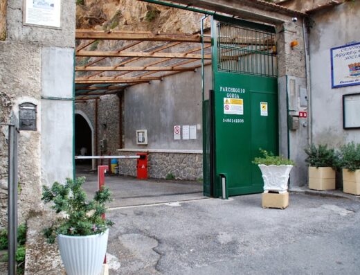Ingresso del Parcheggio Gorga ad Amalfi, con sbarra d'accesso e cartello indicativo. Soluzione ideale per parcheggiare scooter e moto durante la visita della Costiera Amalfitana.