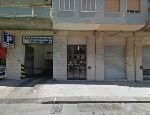 Ingresso di un'autorimessa e autolavaggio con insegna Parking ben visibile, ideale per motociclisti in cerca di servizi per moto e parcheggio sicuro.