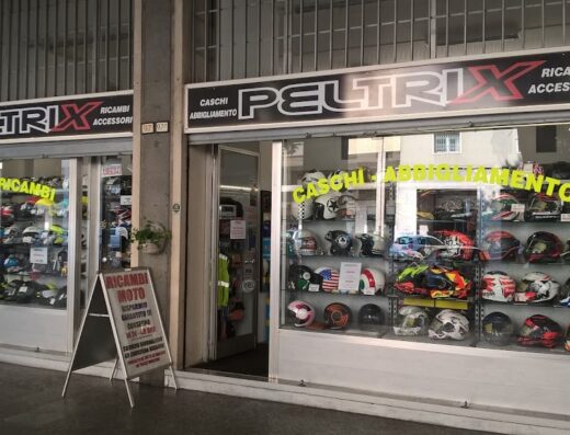 Negozio Peltrix SportSpeed con vetrine espositive di caschi e accessori moto, abbigliamento tecnico e ricambi. Cartello promozionale ricambi moto in evidenza.
