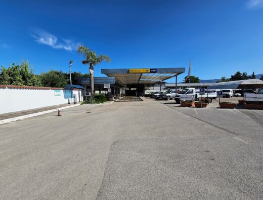 Foto esterna della sede di Perretta Car Srl, con parcheggio auto, uffici e insegna ben visibile sotto un cielo azzurro.