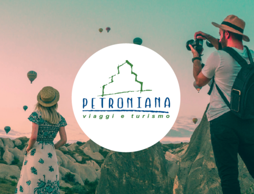 Petroniana Viaggi e Turismo: coppia ammira mongolfiere in Cappadocia, Turchia. Uomo fotografa il panorama, donna con abito a fiori e cappello. Esperienze di viaggio uniche.