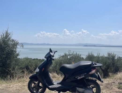 Piaggio scooter nero parcheggiato con vista panoramica sul lago, ideale per esplorare e viaggiare in moto