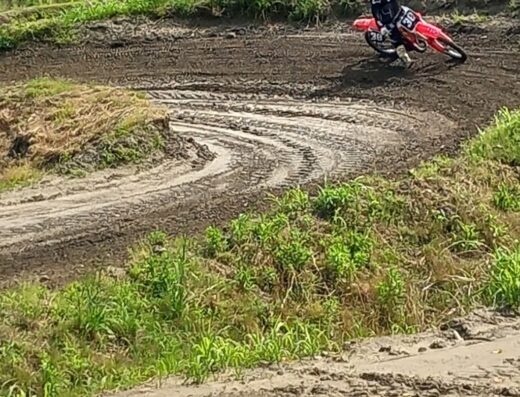 Un pilota di motocross guida una moto rossa su una pista sterrata a Piccola America. Servizi per motociclisti, accessori moto.
