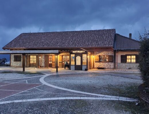 Esterno dell'Hotel Ristorante Pietrapanna, con facciata illuminata, cielo nuvoloso e pavimentazione in pietra. Ideale per viaggiatori in moto alla ricerca di ospitalità e ristorazione.