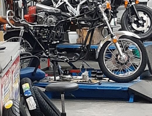 Officina Piscitelli Giovanni: motociclette Suzuki d'epoca in riparazione su ponte sollevatore, con accessori e ricambi in vista. Servizio di assistenza e restauro moto.
