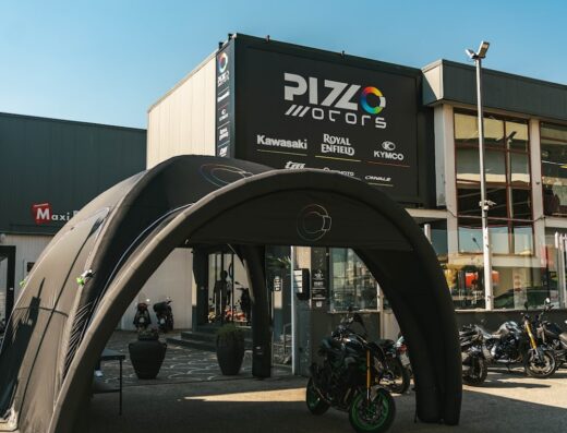Pizzo Motors Srl storefront in Casoria, showcasing Kawasaki, CFMOTO, Kymco, and Ohvale motorcycles with a branded awning and various models on display.