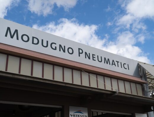 Insegna di Modugno Pneumatici, specialista in pneumatici per moto e auto, con cielo azzurro sullo sfondo e logo Vredestein.