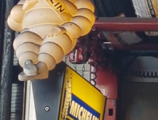 Insegna di Poloni Gomme con l'iconico omino Michelin, simbolo di pneumatici di alta qualità per moto e auto, servizi di manutenzione e riparazione.