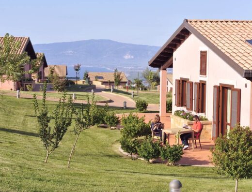 Popilia Country Resort: Vista delle villette con persone sedute all'aperto, ideale per vacanze e relax in un ambiente naturale.