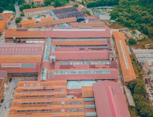 Veduta aerea della sede di PR S.r.l., parte del RIGA Gomme Group, con tetti rossi e strutture industriali immerse nel verde.