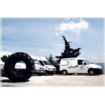 Pneumatico per moto in primo piano, con furgoni bianchi sullo sfondo. Servizio di assistenza stradale per motociclisti.