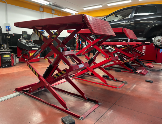 Sollevatori idraulici rossi per auto in un'officina BestDrive, attrezzatura per la manutenzione e riparazione di veicoli.