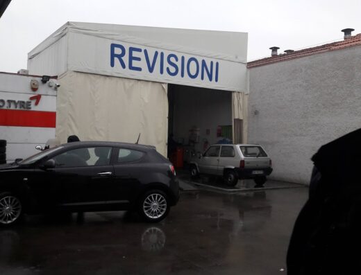 Immagine di Punto Gomma SNC che offre servizi di revisione auto, con vetture in attesa e l'insegna 'REVISIONI' ben visibile.