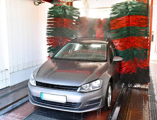 Lavaggio automatico auto: una Volkswagen grigia attraversa i rulli colorati dell'autolavaggio Ramon per una pulizia completa.