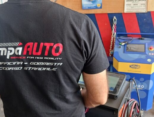 Un uomo con la maglietta di Rampa Auto S.r.l., officina specializzata in servizi di riparazione auto, gommista e soccorso stradale. Sullo sfondo, attrezzature per la diagnostica auto Magneti Marelli.